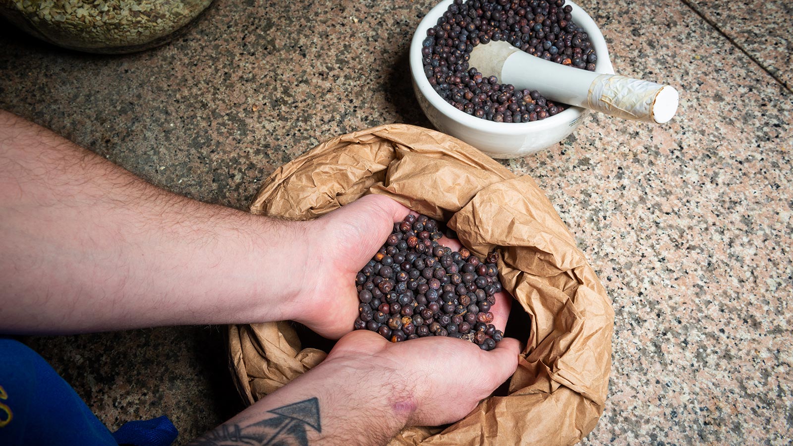 Delle mani raccolgono da un sacchetto dei chicchi pronti per essere distillati.